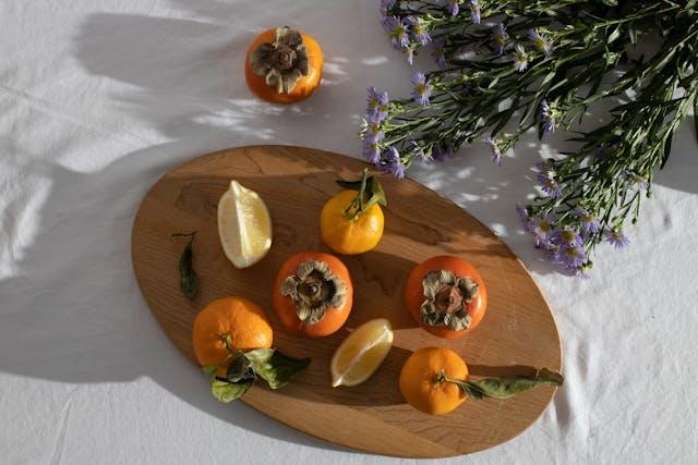 Fresh ripe citruses and persimmon composed with bunch of European Michaelmas daises